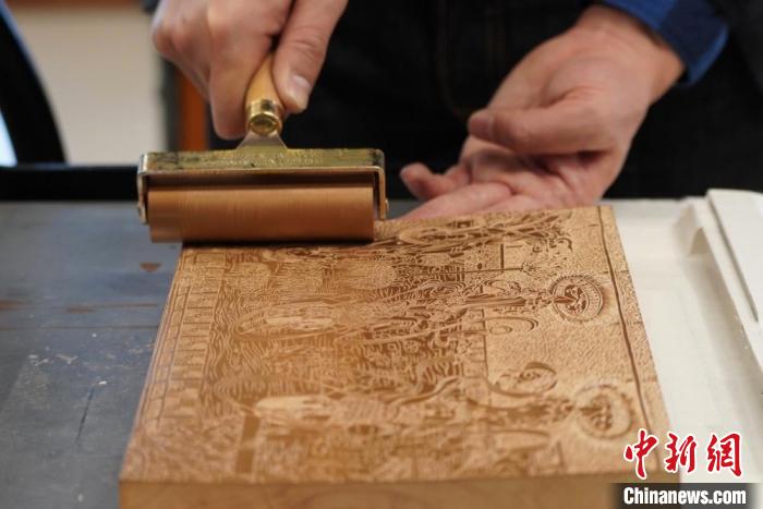 圖為徐晉林工作室工作人員正在給雕好壁畫的版面滾油墨?！【琶赖┰?　攝