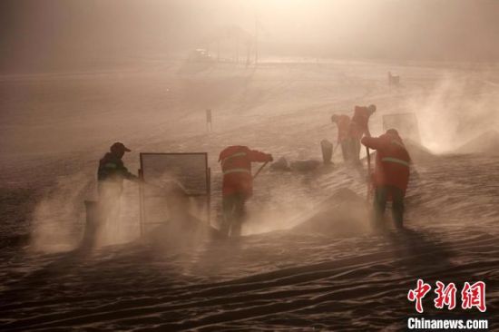 圖為敦煌市鳴沙山月牙泉景區(qū)“駱駝保姆”清理駱駝糞便?！垥粤?攝