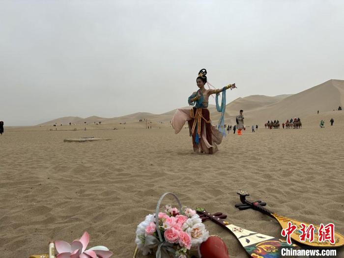 圖為2023年4月底，敦煌大漠“逐舞者”奧楠在鳴沙山月牙泉景區(qū)視頻直播敦煌舞?！●T志軍 攝