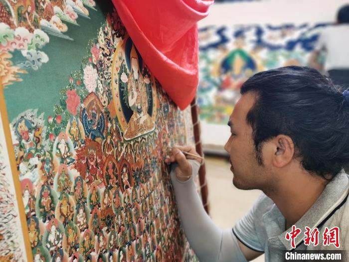 圖為更登才讓的徒弟繪畫唐卡?！?zhí)砀?攝