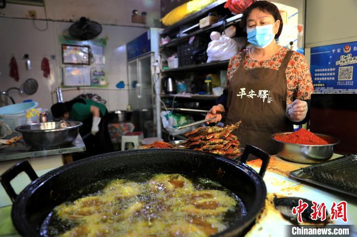 圖為平安驛·河湟民俗文化體驗地內(nèi)的商戶炸干板魚?！⊙Φ?攝